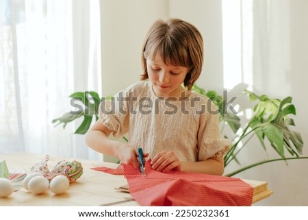 Making Easter eggs in the shape of a hare from textile. The girl prepares the fabric, cuts it with scissors. Home decoration for Easter