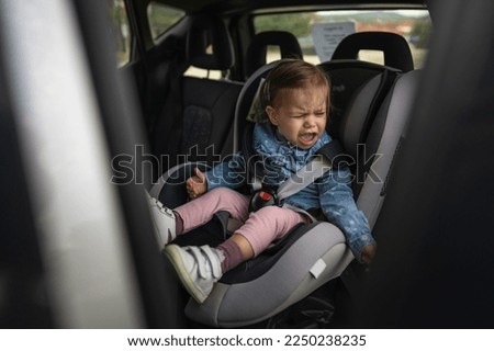 One girl small caucasian toddler female child sitting in the safety car seat chair 18 months old cry protest negative emotion transportation concept copy space Royalty-Free Stock Photo #2250238235
