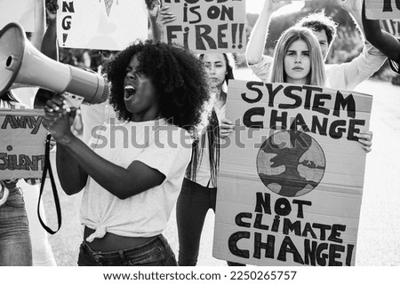 Young group of demonstrators on road from different culture and race protest for climate change - Focus on right sign - Black and white editing