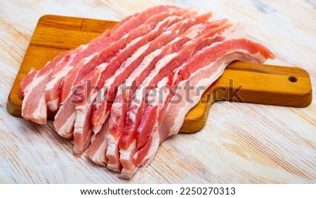 Close up of raw bacon steaks on wooden surface, nobody
