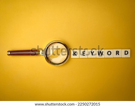 Magnifying glass and toys word with the word KEYWORD on yellow background