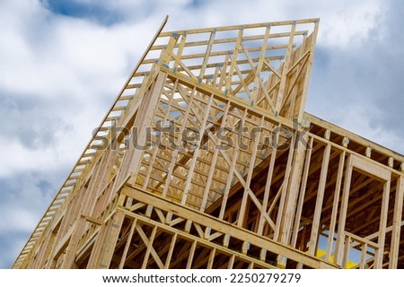New residential construction home framing against a blue sky roofing construction wooden construction board log joist Royalty-Free Stock Photo #2250279279