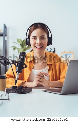 Young Asian woman use microphones wear headphones with laptop record podcast interview for radio. Content creator concept. Royalty-Free Stock Photo #2250336561