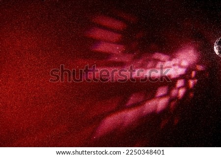 Light pink beams of light on a gradient red finely grained background