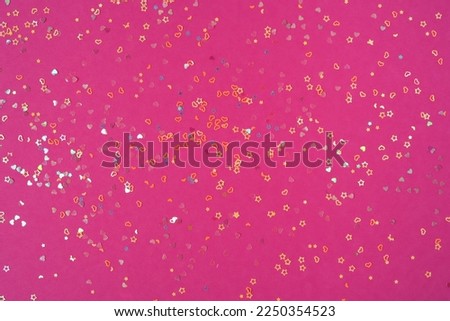 Multicolored sequins in the shape of a heart and a star on a pink background