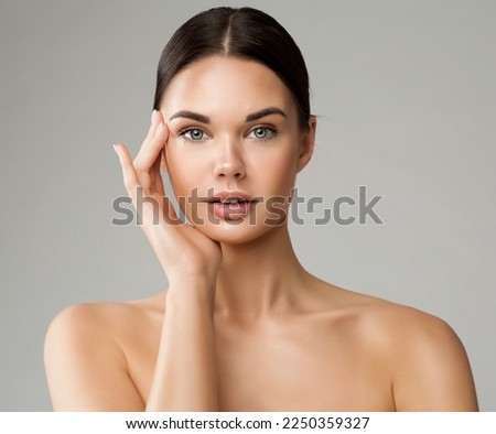 Beauty Woman Face with Perfect Smooth Skin. Young Model applying Eye Cream. Beautiful Girl with Full Lips Natural Makeup over White. Women Facial Plastic Surgery and Dermal Fillers Royalty-Free Stock Photo #2250359327