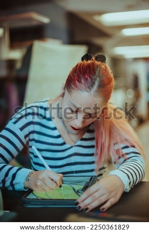 Tattoo artist with red hair drawing car on her tablet in the studio
