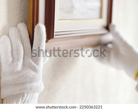 Gloved hand holding a picture frame Royalty-Free Stock Photo #2250363221