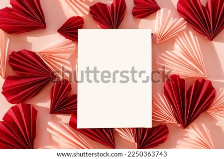 Empty card and stylish red and pink hearts flat lay on pink paper background. Creative modern valentines greeting card mock up with space for text. Happy Valentine's day! Love letter