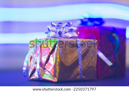New Year's gift in a bright package against the background of Christmas decorations and bright lights of the garland..