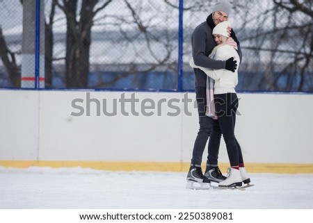 Wisome Young Caucasian Couple in Winter With Ice Skates Posing Together Over a Snowy Winter Landscape Outdoor. Horizontal Shot