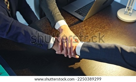 Business people forming a circle in a dark office. Royalty-Free Stock Photo #2250389299