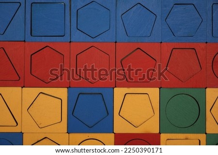 Wooden puzzle with different geometric shapes and colors as background, top view. Montessori toy Royalty-Free Stock Photo #2250390171
