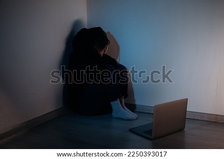 Teenager female girl sitting in a dark room in front of laptop, concept of cyber bullying Royalty-Free Stock Photo #2250393017