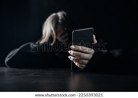 Young teenager female girl with smartphone in her hand felling lonely and hopeless. Online bullying and harassment concept. Royalty-Free Stock Photo #2250393021