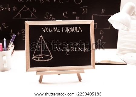 Blackboard with hand written geometry volume formulas and geometric shapes and figures
