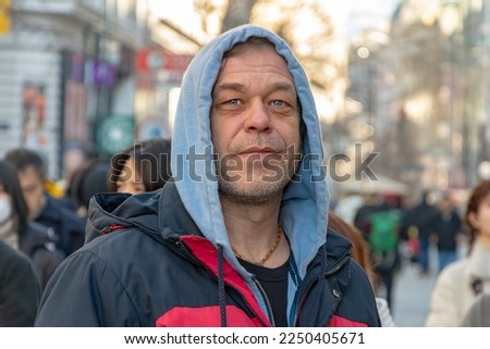 Street Portrait of an elderly man 45-50 years old on a blurry background of a street and a crowd of people in a European city. Royalty-Free Stock Photo #2250405671