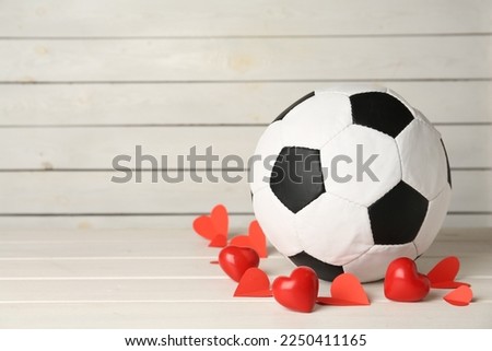 Soccer ball and hearts on white wooden table. Space for text