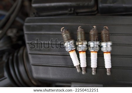 Spark plugs with worn electrodes. Used, burned four spark plugs. Electrical ignition engine spare parts, spark plug on black background. Ignition system problem. Replacing spark plugs. Selective focus