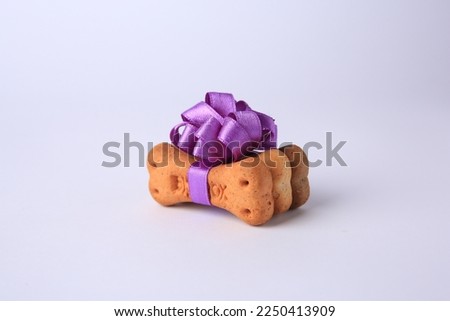 Bone shaped dog cookies with purple bow on white background Royalty-Free Stock Photo #2250413909