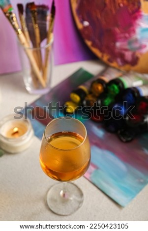 Glass of tasty wine, colorful paints and canvas, above view. Space for text