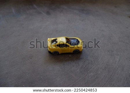 small car toy. yellow toy car facing right, photographed from above