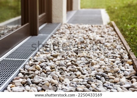 French drain, Drain Stones Gravel Floor, Drainage Surface system for Storm Water around Perimeter House with Stainless Steel Grid or Mesh Royalty-Free Stock Photo #2250433169