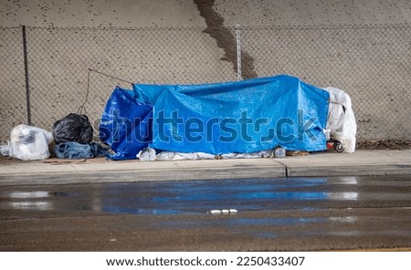 Homless shelter in the rain under a freeway bridge Royalty-Free Stock Photo #2250433407