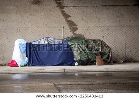 Homless shelter in the rain under a freeway bridge Royalty-Free Stock Photo #2250433413