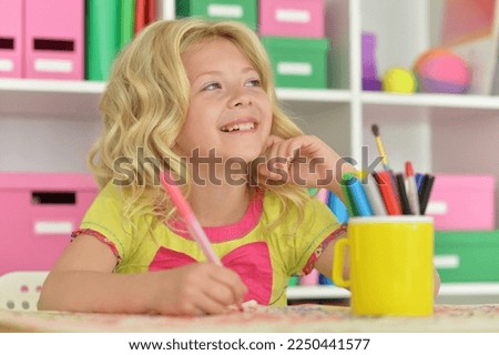 Cute girl drawing picture at desk at home