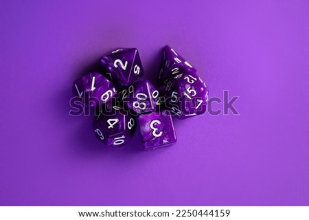 Lots of purple RPG dice, extreme closeup, banner. Role playing board games symbol, scattered set of simple polyhedral dice showing random numbers. Collection of beautiful polyhedral dice