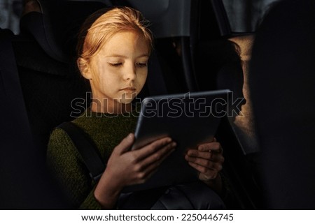 Girl watching cartoons during trip by car
