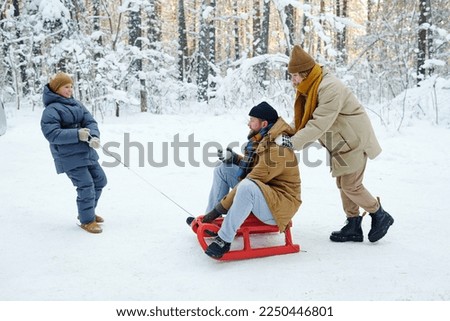 Family sledding in park in winter
