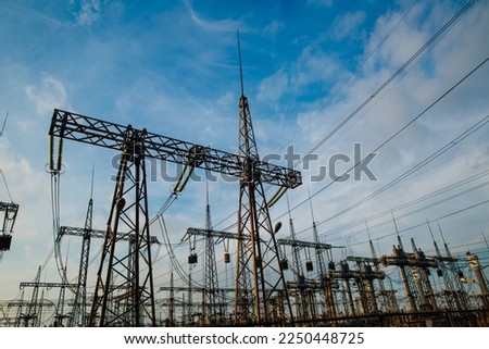 Electrical pylons and high voltage power lines are behind a barbed wire fence. critical infrastructure Royalty-Free Stock Photo #2250448725