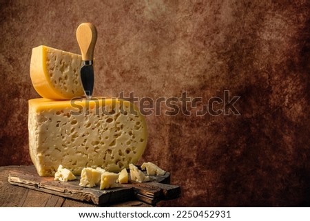 close up french hard cheese with holes emmentaler on a wooden background. farmer market. vertical image. place for text. Royalty-Free Stock Photo #2250452931