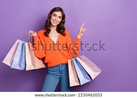 Photo of young fashionista cheerful woman stylish outfit hold bags shopping center customer point finger mockup isolated on purple color background