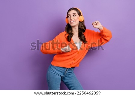 Photo of young lady with wavy brunette hair dance vibe celebrate have fun listen headphones look empty space isolated on purple color background
