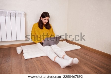 A girl is sitting on the floor in the house and working on a laptop. 