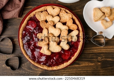 Plate with sweet strawberry pie and heart-shaped plate of cookie hearts for Valentine's day on wooden background Royalty-Free Stock Photo #2250468319