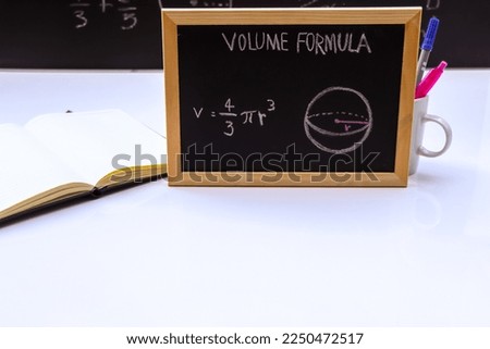 Blackboard with hand written geometry volume formulas and geometric shapes and figures