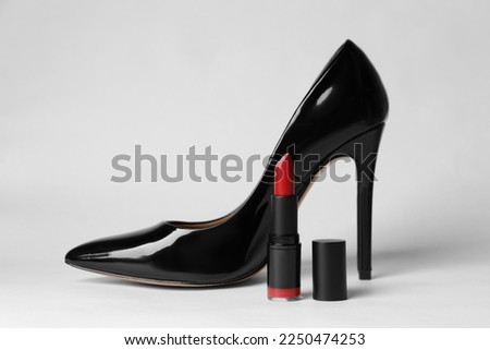 Beautiful red lipstick and black high heeled shoe on white background Royalty-Free Stock Photo #2250474253