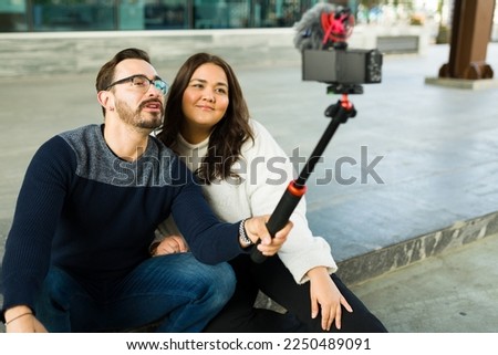 Smiling influencer couple filming a video blog and content with a camera for their social media and followers