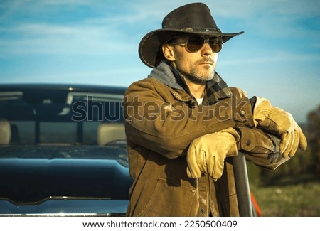 Caucasian Rancher Wearing Cowboy Hat and Sunglasses Staying in Front of His Pickup Truck. American Farmer Theme.
