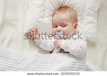 Cute five month old baby sleeping in comfortable bed. Concept of the family andparenting. Royalty-Free Stock Photo #2250502515