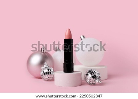 Composition with lipstick and Christmas balls on pink background