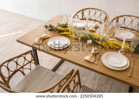 Beautiful table setting with mimosa flowers and candles in room