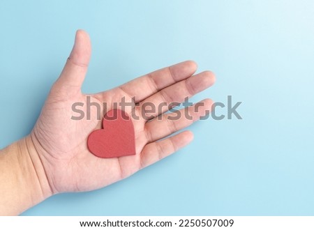 red wooden heart shape piece in human hand