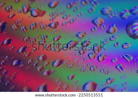 Drops of water on a CD-ROM. Colourful background. Some drops in focus. Macro shot.