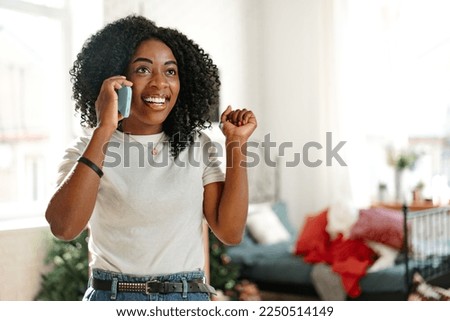 African young woman talking on a mobile phone at home Royalty-Free Stock Photo #2250514149