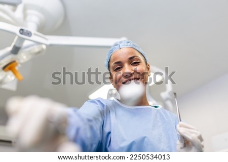 Portrait of happy woman surgeon standing in operating room, ready to work on a patient. Female medical worker in surgical uniform in operation theater.